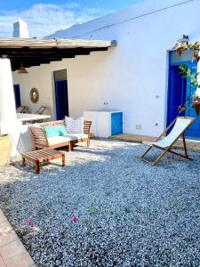 un patio avec deux chaises et un banc ainsi qu'un bâtiment dans l'établissement Villa Euribia, à Santa Marina Salina