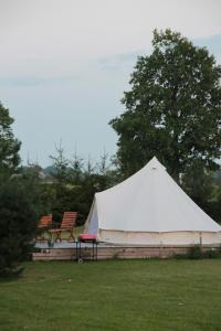 a white tent in a field with two chairs at Casa de campo glamping in Eželiškės +66 photos