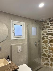 uma casa de banho com um chuveiro e um lavatório. em Vourtaréa Guesthouse em Himare