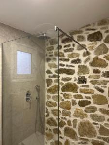 uma casa de banho com um chuveiro e uma parede de pedra em Vourtaréa Guesthouse em Himare