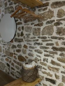 uma parede de pedra com um espelho e um cesto numa prateleira em Vourtaréa Guesthouse em Himare