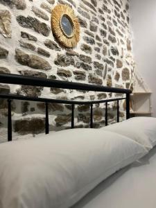 uma cama em frente a uma parede de pedra com um espelho em Vourtaréa Guesthouse em Himare