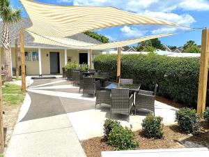 eine Terrasse mit Tischen und Stühlen unter einem großen Sonnenschirm in der Unterkunft Beau Rivage Golf and Resort in Wilmington