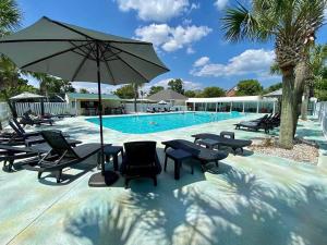 basen z krzesłami i parasolem obok basenu w obiekcie Beau Rivage Golf and Resort w mieście Wilmington