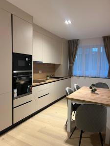 a kitchen with a wooden table and a dining room at Luxury Sunny Apartments near City Center Suceava in Suceava