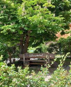 un banco de madera sentado bajo un árbol en un parque en Steurer Hof, en Liebenfels
