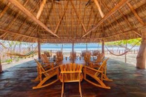 un restaurante con sillas, mesas y techo de paja en Casa Yosi, Beach Front Piece of Heaven en San Juan del Sur