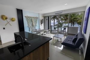 a kitchen and living room with a view of the ocean at Angelina 28 Beachfront and Family Apartments - Modern and Relaxing Long Stays - 20 min from Cancun Airport in Puerto Morelos