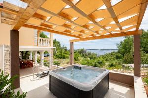a hot tub on a patio with a wooden pergola at Villa Franciska in Blato