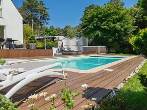 a swimming pool with a wooden deck next to a house at Villa Raphia - Maison d'hôtes in Hardelot-Plage