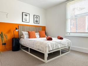 een bed met oranje en witte kussens in een kamer bij Love Lane - Cosy & Modern City Centre Guest Suite in Canterbury