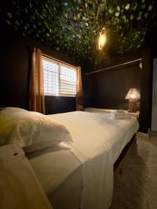 1 dormitorio con 1 cama con colcha blanca y ventana en Watermelon House, en Santa Bárbara de Samaná