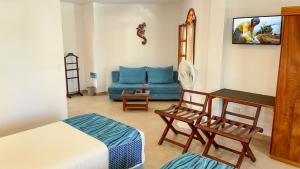 a living room with a bed and a blue couch at Hotel Galapagos Suites B&B in Puerto Ayora