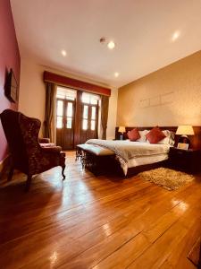 a bedroom with a large bed and a chair at Pepe's House Cuenca I Hotel & Boutique Hostel in Cuenca