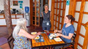 プエルトアヨラにあるHotel Galapagos Suites B&Bの三人の女がテーブルに座って食べ物を食べる
