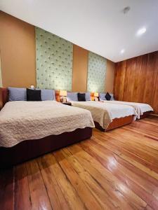 duas camas num quarto de hotel com pisos de madeira em Pepe's House Cuenca I Hotel & Boutique Hostel em Cuenca