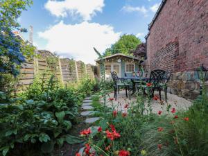 un jardín con mesa y sillas junto a una pared de ladrillo en Red Grouse Cottage en Guisborough