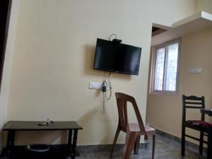 Zimmer mit einem Tisch und einem TV an der Wand in der Unterkunft PR Residency in Tiruvidaimarudūr