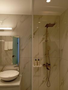 a bathroom with a sink and a glass shower at Ifestia Hotel in Kamari