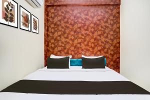 OYO Hotel Mid Town في بيلاسبور: غرفة نوم بسرير وجدار احمر