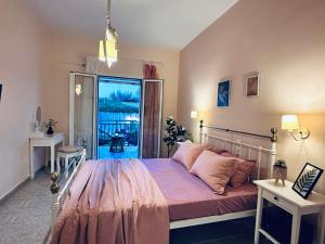 um quarto com uma cama com lençóis cor-de-rosa e uma varanda em Royal Jelly Suites em Marathias