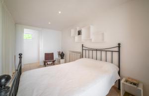 een witte slaapkamer met een bed en een stoel bij Villa Cana Chana in Santa Gertrudis de Fruitera