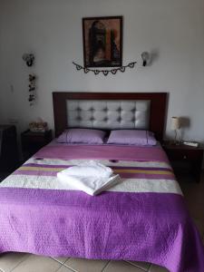 - un lit violet avec un livre au-dessus dans l'établissement Séduisant Studio vue piscine Cabo négro, à Cabo Negro