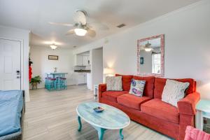 a living room with a red couch and a table at Walk to Pier St Augustine Beach Condo with Balcony! in Saint Augustine Beach
