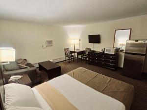 Habitación de hotel con cama y sala de estar. en Canadian Motor Inn en Grande Prairie