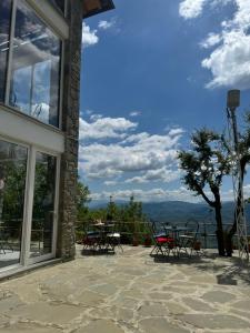 a patio with tables and chairs and a view of the mountains at Xhaferri Guesthouse in Çorovodë