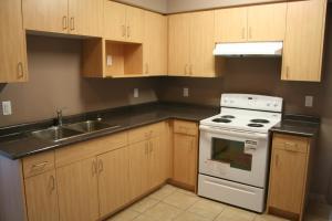 a kitchen with wooden cabinets and a white stove top oven at Hotel Laurier - Apartment Style Residence in Waterloo +7 photos