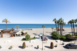 uma vista para uma praia com palmeiras e um carro em Hotel Mediterráneo em Estepona