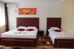 um quarto com 2 camas e almofadas vermelhas em Hotel Venisi em Prizren