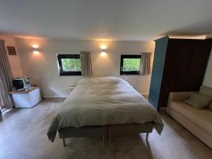 een slaapkamer met een groot bed en een bank bij La Grange 28 in Bergen op Zoom