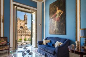 a living room with a blue couch and a large window at Cathedral View Apartments in Palermo