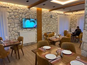 restauracja z drewnianymi stołami i kamienną ścianą w obiekcie Oda N'Bjeshke w mieście Valbonë