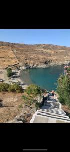 a person is sitting on a path next to a river at Kanala house in Kithnos +4 photos