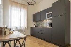een keuken met grijze kasten en een tafel in een kamer bij ThreeMoonsBoutique House/Pandora in Salerno