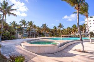 una piscina con palmeras y edificios en Luxury Beach Residences, en Puerto Morelos
