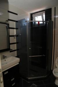 uma casa de banho com uma cabina de duche em vidro e um lavatório. em Hotel Venisi em Prizren