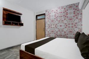 1 dormitorio con 1 cama y pared con TV en OYO Hotel Royal Park, en Alwar