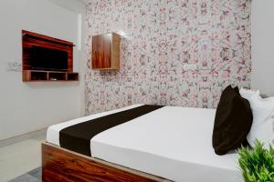 1 dormitorio con cama blanca y papel pintado con motivos florales en OYO Hotel Royal Park, en Alwar