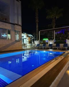 a swimming pool at night next to a building at Amsterdam Otel Economic Room in Kemer