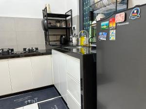 eine Küche mit weißen Schränken und einem schwarzen Kühlschrank in der Unterkunft Holiday Inn Stay 3B2R Meritus Residensi Perai in Perai