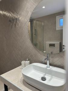 ein Badezimmer mit einem weißen Waschbecken und einem Spiegel in der Unterkunft Kavos Hotel in Patitiri