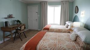 a hotel room with two beds and a desk and a desk at The Savannah Inn in Carolina Beach