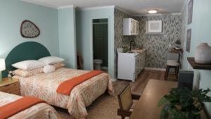 a bedroom with two beds and a table and a kitchen at The Savannah Inn in Carolina Beach