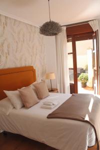 a bedroom with a large white bed with a window at Alojamiento “El Maltés” in Cudillero