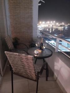 a table and chairs with wine bottles and glasses on a balcony at Departamento esmeralda Iquique x dia in Iquique