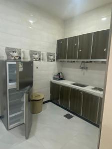 a kitchen with brown cabinets and a white floor at حي بلاس للأجنحة الفندقية in Najran